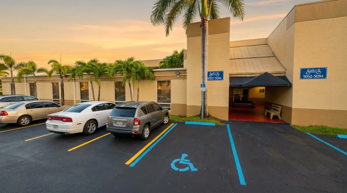 Fachada del edificio de 5092 NW 74th Ave en Miami al atardecer, con el letrero de las suites 5052-5094, la entrada y el estacionamiento